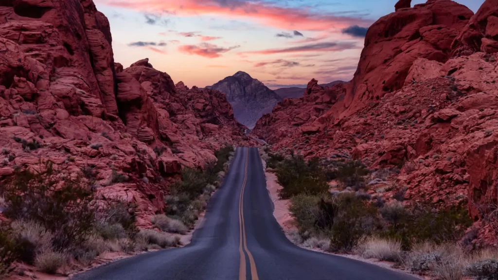 A picture of a road in Nevada that is surrounded by mountains and a desert landscape.