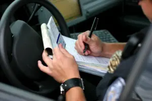 A police officer issuing a ticket in their car.