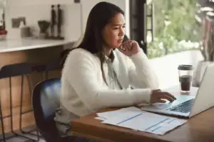 A woman on the phone while looking through her computer.
