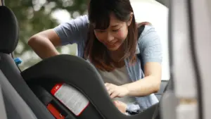 A woman setting up a booster seat in her car. 